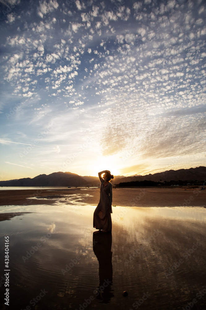 Fototapeta premium Beautiful woman dancing by the sea at sunset