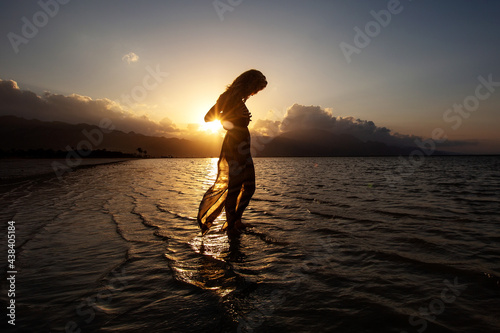 Beautiful woman dancing by the sea at sunset © Maygutyak
