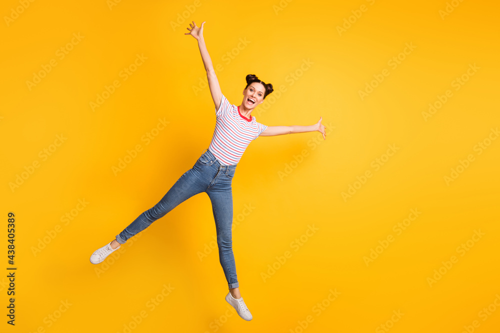 Full length photo of charming sweet young lady wear striped t-shirt jumping like star isolated yellow color background