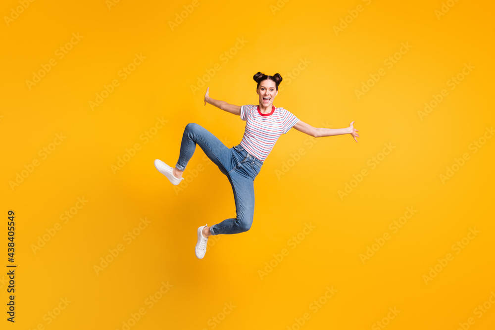 Full length photo of pretty adorable young girl dressed striped t-shirt jumping high isolated yellow color background