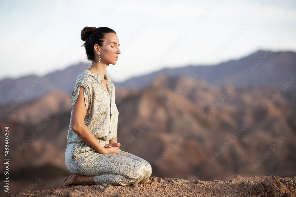Woman practicing yoga in the mountains in the desert Woman practicing yoga in the mountains in the desert