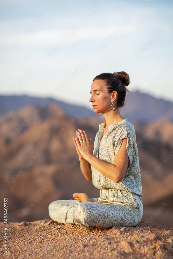 Woman practicing yoga in the mountains in the desert