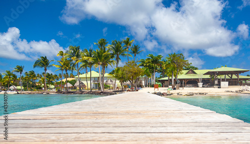 View from the wooden pier to the picturesque island of Martinique in the French Antilles. Relax in Martinique in sunny weather among palm trees, clear turquoise water and clean sand.