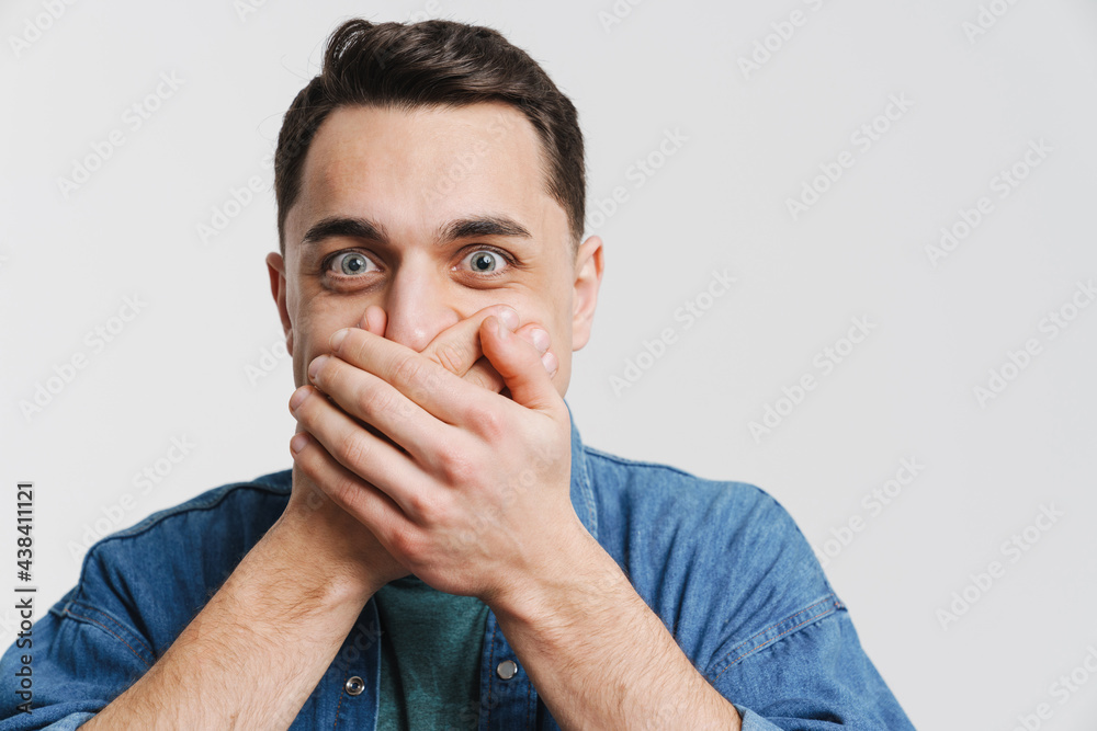 Young excited man covering his mouth and looking at camera Young excited man covering his mouth and looking at camera