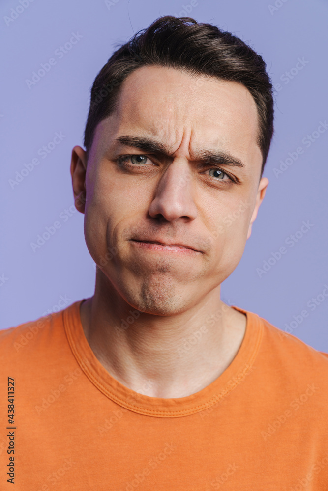 Fototapeta premium Young brunette white man frowning and looking at camera