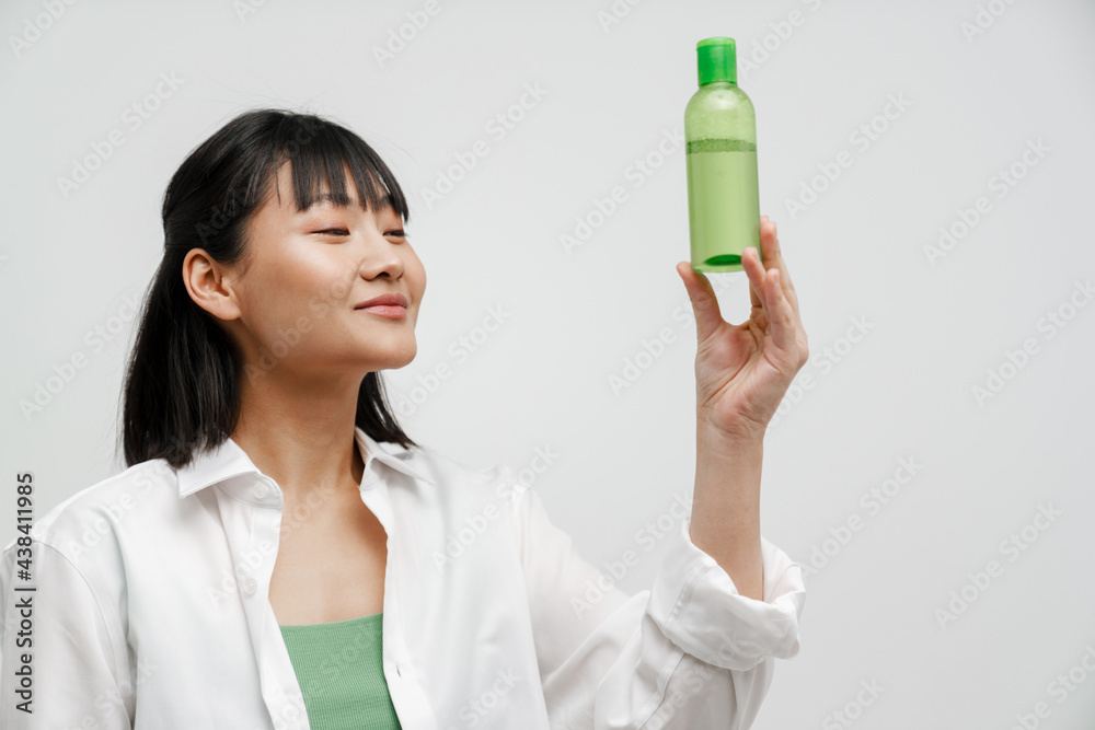 Young asian woman smiling while showing facial lotion Young asian woman smiling while showing facial lotion