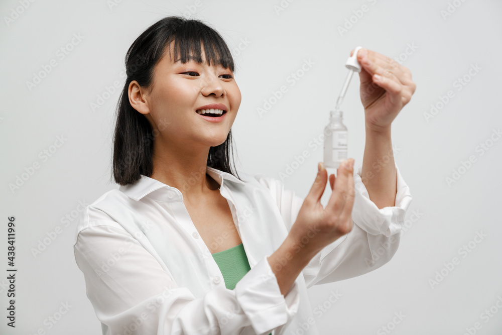 Young asian woman smiling while showing facial serum Young asian woman smiling while showing facial serum