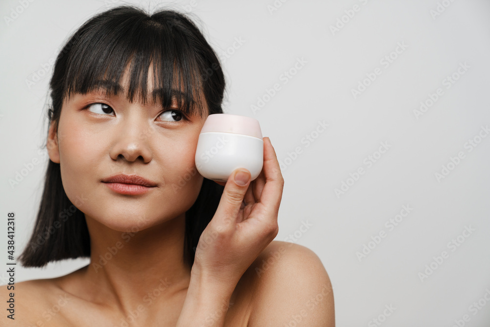 Young asian shirtless woman posing with face cream Young asian shirtless woman posing with face cream