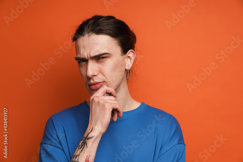 Young white man with earring frowning and looking at camera