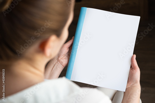 top view of a woman reading an open book or magazine. empty page. mock up