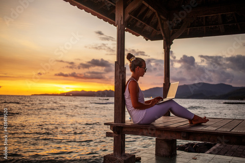 Woman by the ocean working on a laptop © Maygutyak