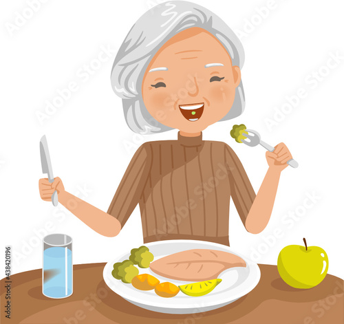 Elderly woman eating. She is sitting Eat fish steak on the table, apple and glass