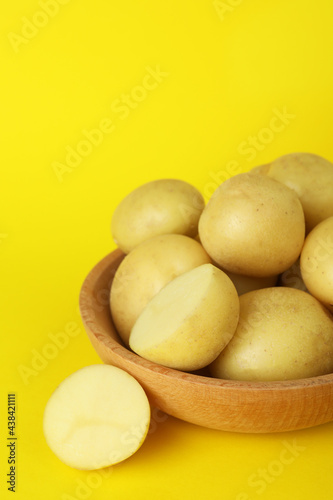 Bowl of young potato on yellow background