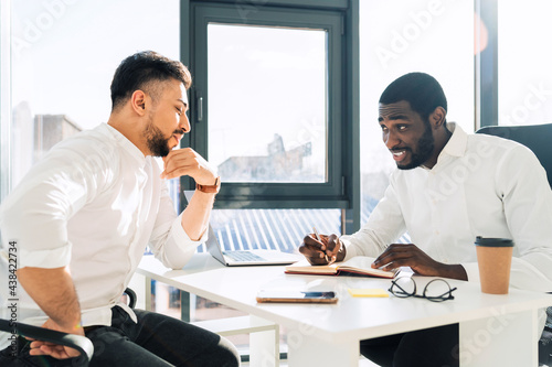 Two mulracial office workers hold meeting in the office