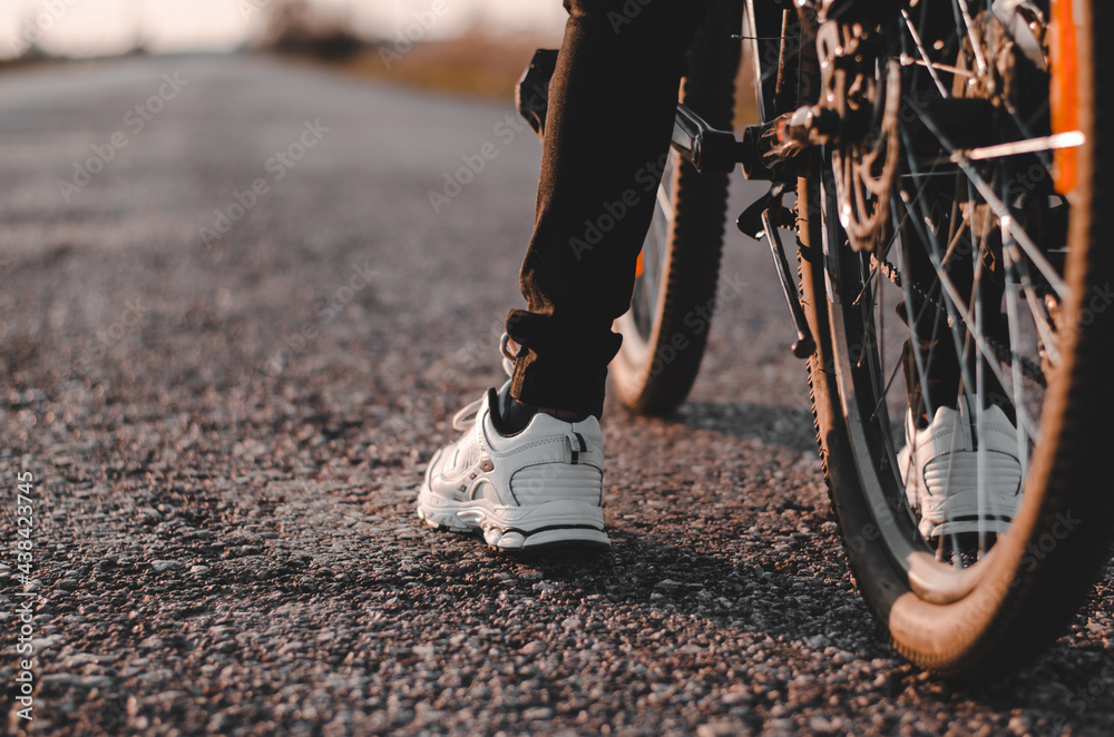 Obraz premium Rear view of the legs and bike of an unrecognizable teenager. Bicycling. Healthy lifestyle concept