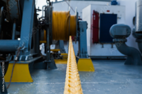 Marine hydraulic winch for mooring operations with yellow ropes wound around it. photo