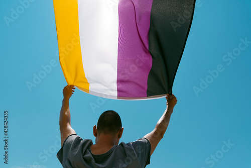 person waving a non-binary pride flag photo
