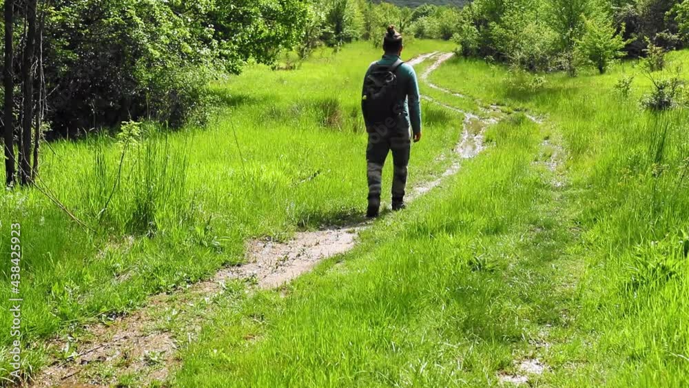 A man walks on the meadow with green grass during spring A man walks on the meadow with green grass during spring