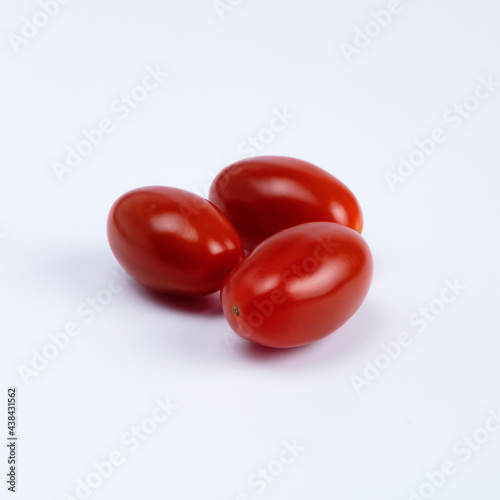 Three oval plums, small tomatoes on a distinctly white background..