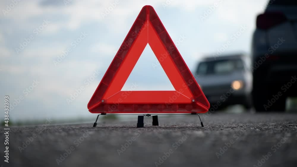 Reflecting warning triangle on the road behind the broken car