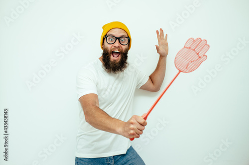 Slika na platnu Young caucasian hipster man holding a fly swatter wanting to kill annoying mosquito or a fly