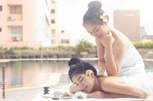 Asian women relaxing massage treatment with joyful mood together at the edge of swimming pool.Wellness body care and spa aromatherapy concept.