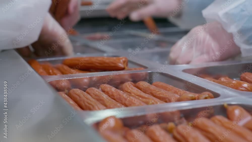 Workers of the cooked meats plant distribute ready-made sausages in plastic packages for further transporation Workers of the cooked meats plant distribute ready-made sausages in plastic packages for further transporation