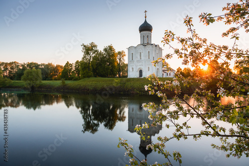 Church of the Intercession on the Nerl in Bogolyubovo, Russia. Famous landmark of the Golden Ring of Russia. Beautiful summer landscape with blooming apple tree at sunrise. photo