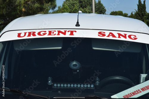 Bandeau Urgent Sang sur une voiture de transport de poche de sang.