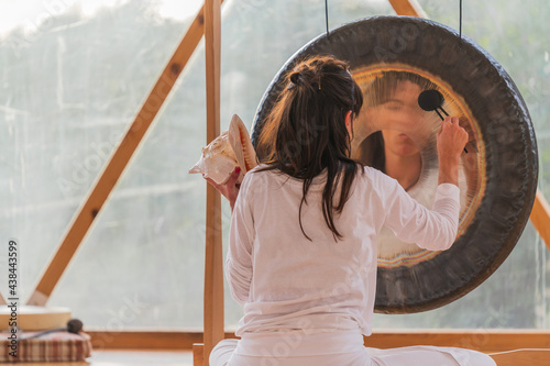 Spiritual woman hitting gong while calm people lying on yoga mats with eyes closed in yoga class photo