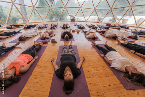 Calm people lying on yoga mats with eyes closed in yoga class photo