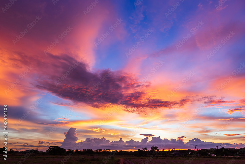 Obraz premium Twilight blue bright and orange yellow dramatic sunset sky in countryside or beach colorful cloudscape texture with white clouds air background.