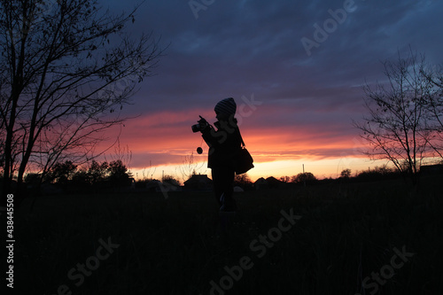 Silhouettes of a boy with a camera on the background of sunset