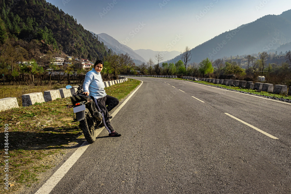 Fototapeta premium girl sitting at motorcycle at tarmac road with beautiful natural view at morning