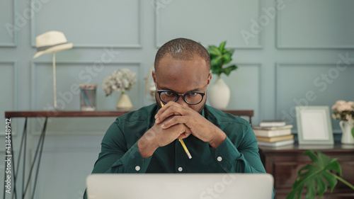 Obraz na płótnie young african American man is thinking in front of a laptop. w salonie