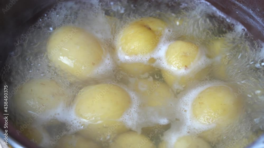 Close-up view of boiling water with yellow raw potatoes in a saucepan. Young potato are boiled in boiling water