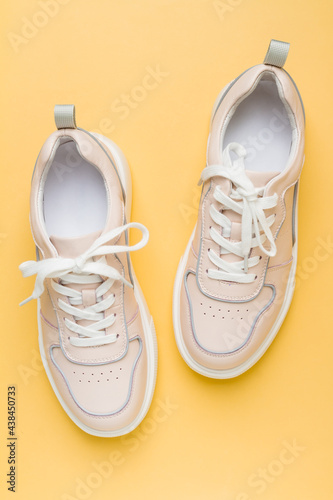 New, clean sneaker shoes. Soft pink colored women's sneakers on a yellow orange background