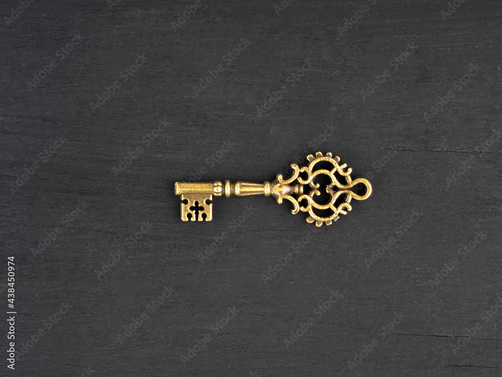 Obraz premium Bronze color antique key on black wooden background