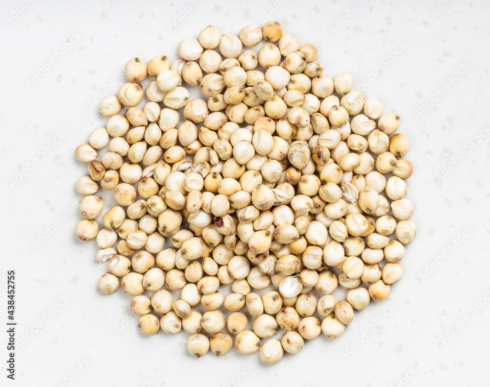pile of raw unpolished Sorghum grains on gray pile of raw unpolished Sorghum grains on gray