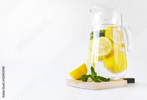 a pitcher of lemons and mint on a wooden board