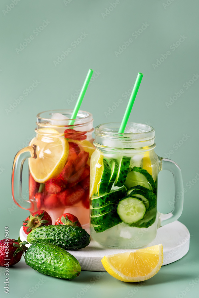 Variety of Cold Summer Drinks in Glass Jars Infused Detox Water with Cucumber Lemon and Strawberry Healthy Drink Green Background Vertical