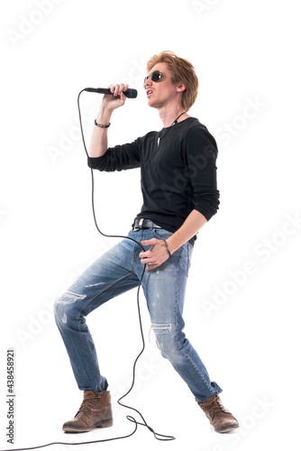 Side view of energetic passionate rocker singer singing loud on microphone. Full body length isolated on white background.