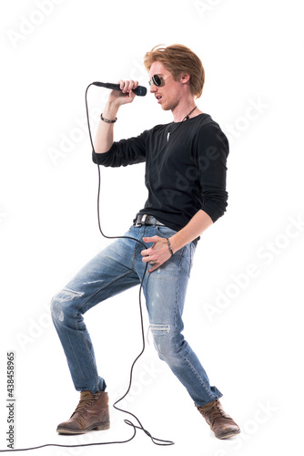 Side view of passionate rocker singing on microphone bending backwards. Full body length isolated on white background.