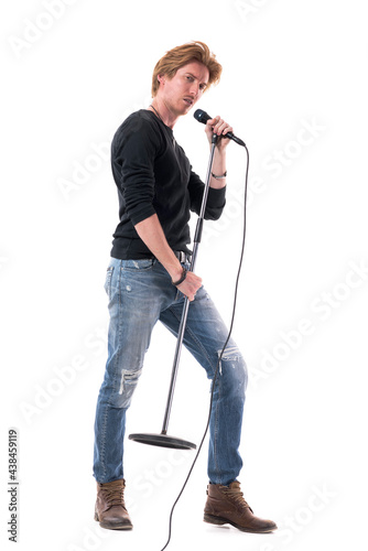 Side view of macho rock music singer man singing on microphone on stand. Full body length isolated on white background.