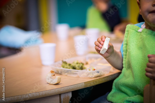 Foto enfant qui mange du fromage lors d'une repas dans une crèche