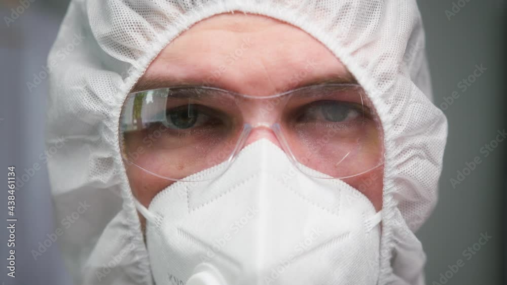 Close-up of overworked doctor or researcher dressed in protective suit ppe mask in laboratory in hospital, male nurse wearing medical uniform, portrait of tired man chemist in protect safety glasses. Close-up of overworked doctor or researcher dressed in protective suit ppe mask in laboratory in hospital, male nurse wearing medical uniform, portrait of tired man chemist in protect safety glasses.