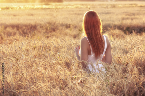 Beauty redhead girl in white dress outdoors enjoying nature. Free happy woman in warm colors on sunset
