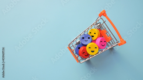 A shopping cart and colorful crudes with a smile inside. A symbol of happy shopping