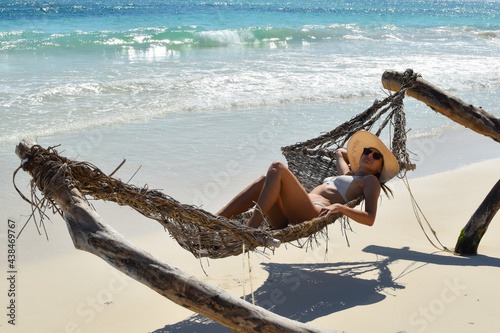 A woman in a swimsuit sunbathes in a hammock on a tropical beach. picturesque exotic landscape. sunbathing at sea