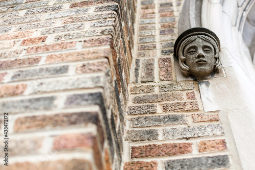 Stone face looks down from brick wall